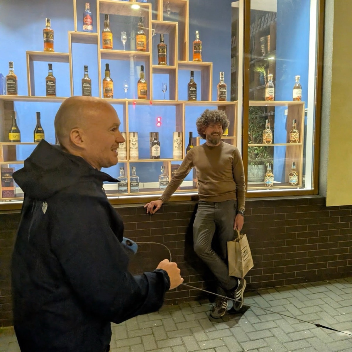 Two members in front of the whisky shop