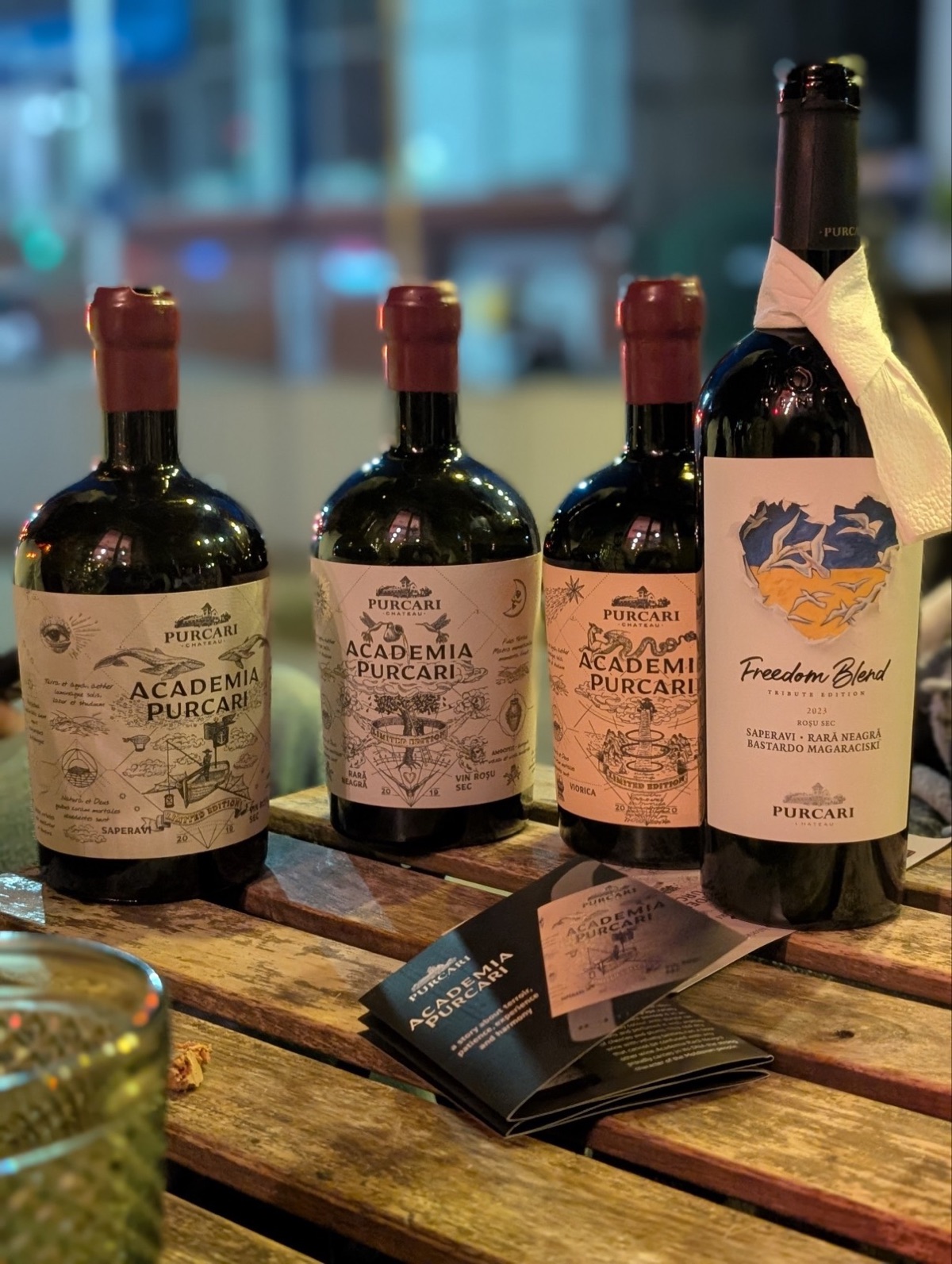 Cele patru sticle pe masă - trei Academia Purcari și un Freedom Blend, lângă broșura seriei
