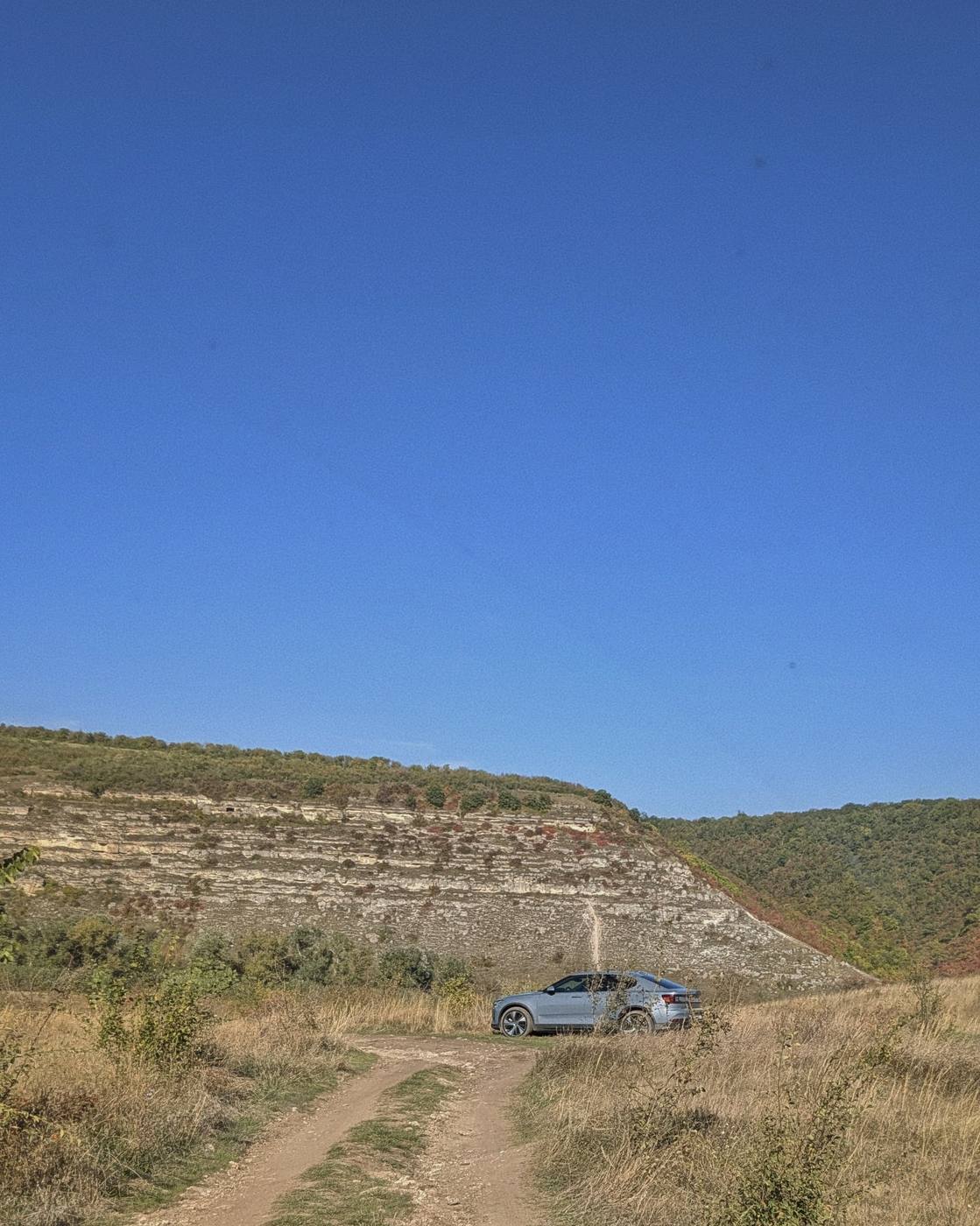 The car down on a dirt road, below a limestone bank